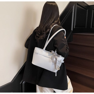 Détail du sac sous l'aisselle en cuir ciré bleu clair avec ruban et breloque ours