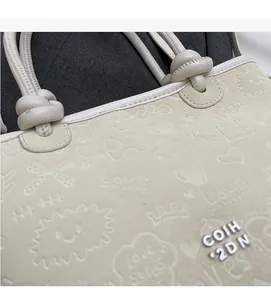 Detail of beige bucket bag featuring embossed heart patterns and metal side logo