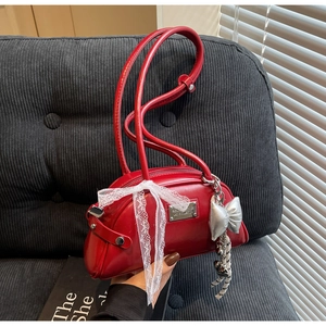 Détail d'un sac bowling rouge avec nœud en dentelle et breloques papillon argentées