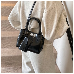 Détail du sac Kelly en cuir verni noir avec fermoir argenté et mini pochette décorative
