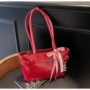 Détail du sac en cuir verni rouge brillant avec nœud et pendentif cœur en argent