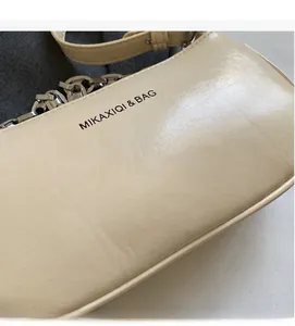 Gros plan du sac bandoulière en similicuir crème avec texture plissée et chaîne argent
