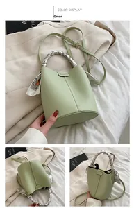 Detail shot of green lychee leather bucket bag featuring a decorative silk scarf handle