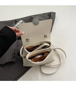 Detail view of the spacious inner compartments and secure silver twist lock of the cream bag