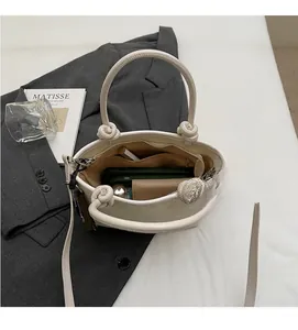 Top view showing spacious interior with zipper pocket in cream bucket bag with items