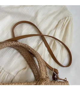Detailed shot of woven handles and leather strap on this summer straw tote bag