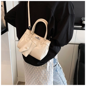 Détail d'un sac à main beige crème en cuir verni brillant avec fermoir en métal et breloque
