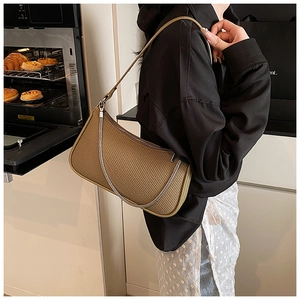 Brown woven texture hobo bag worn on shoulder with silver chain and slim strap