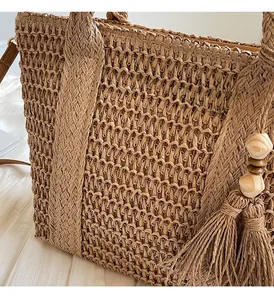 Close-up of hand-woven straw tote bag with decorative tassels and wooden beads