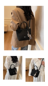 Detail view of black embossed bucket bag with COIN 2DN logo and cute bear pendant charm