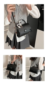 Detail of black litchi leather square bag featuring an elegant silk scarf wrapped handle