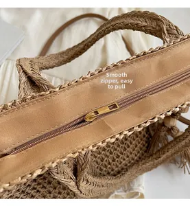 Detail shot of smooth golden zipper closure and woven texture on a khaki straw tote bag