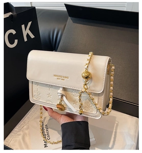 Close-up of embossed star pattern and gold chain strap on an off-white leather bag