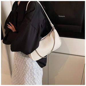 Detail of white woven texture shoulder bag with silver zipper and slim strap design