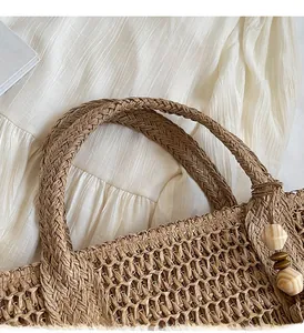 Close-up of woven straw tote bag with sturdy handles and decorative wooden beads