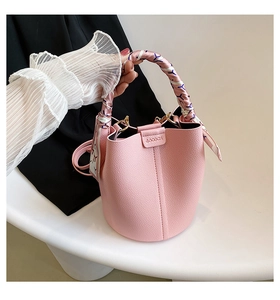 Close-up of pink bucket bag with litchi grain leather and silk scarf wrapped handle