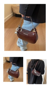 Détail du sac sous le bras en similicuir brillant bordeaux avec chaîne et pendentif argent