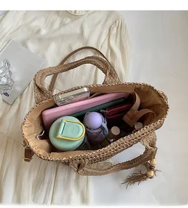 Spacious interior of woven straw tote bag filled with daily items like a tablet and umbrella