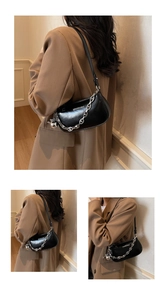 Gros plan du sac bandoulière en cuir noir brillant avec chaîne argentée et breloque boule