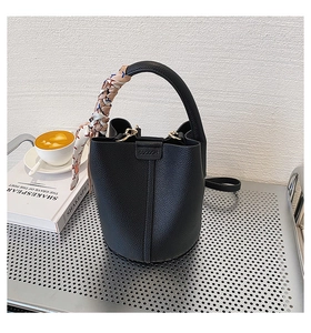 Detail of black lychee-textured bucket bag with decorative silk scarf on handle