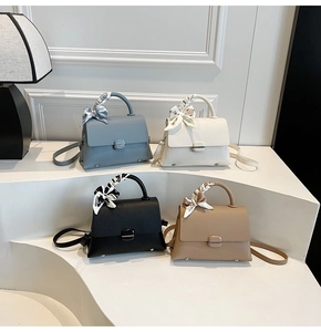 Detailed display of four color leather handbags with silk scarves on a geometric stand
