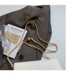 Detail of adjustable golden ball on white faux leather bag with woven chain strap