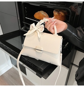 Detail of creamy white litchi grain leather handbag with floral silk scarf handle decoration