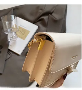 Detailed close-up of cream leather crossbody bag with golden chain and metallic lock