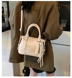 Detail of cream-white soft leather Boston bag featuring embossed text and adjustable strap
