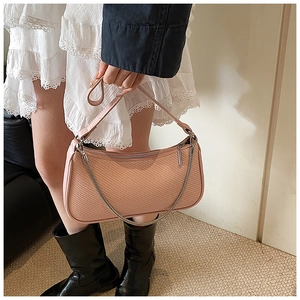 Close-up of pink woven texture shoulder bag with stylish silver metal chain detail