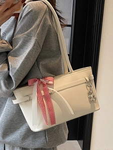 Sac seau beige chic avec nœud vichy rouge et breloque cœur porté à l'épaule par un mannequin