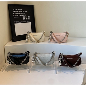Cinq sacs demi-lune à chaîne en diverses couleurs sur des marches d'exposition
