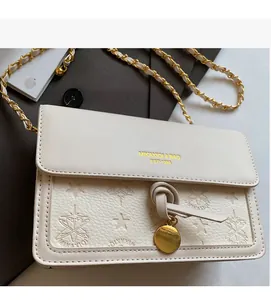Detail of cream white leather crossbody bag with embossed star patterns and gold chain strap