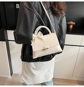 Detail of white litchi leather bag featuring a decorative floral silk scarf on handle