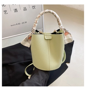 Detail of pistachio green bucket bag with lychee texture and floral silk scarf on handle