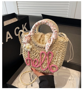 Detail of straw handbag with hello lettering, floral decor and silk handle wrap