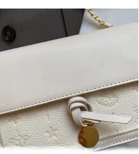 Close-up of star embossed white leather with gold logo and metallic chain strap detail