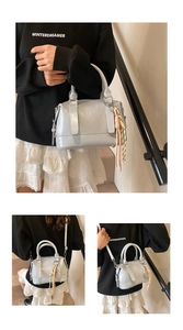 Macro shot of light blue boston bag with embossed text and colorful woven tassel charm