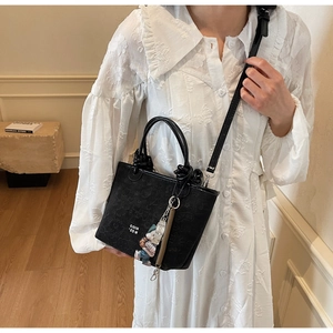 Detail of black jacquard bucket bag featuring vintage patterns and white letter print
