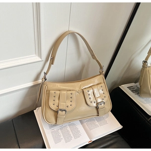 Detail view of beige underarm bag featuring silver rivets and stylish double pocket design
