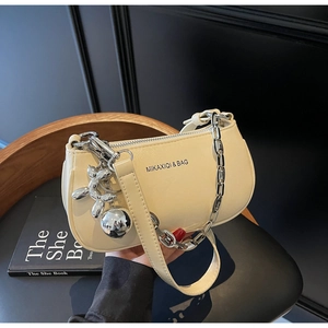 Détail du sac à bandoulière en cuir crème avec chaîne argentée et breloque chien