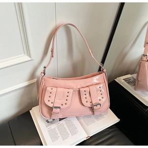 Detail of pink patent leather baguette bag featuring silver studs and dual front pockets