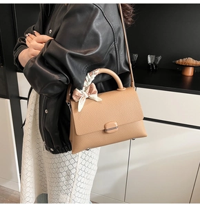 Detail of khaki lychee grain leather handbag with silk scarf handle and metal feet