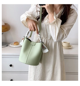 Detail of mint green bucket bag featuring lychee grain leather and silk scarf handle