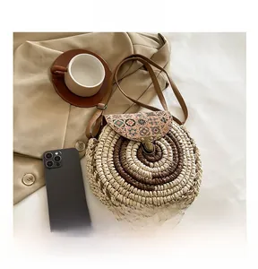 Macro detail of round straw bag with ethnic floral flap and bronze snap button