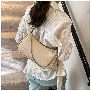 Detail of beige woven baguette bag with stylish silver chain strap and leather trim