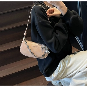 Détail du sac à bandoulière en cuir rose poudré avec grosse chaîne argentée et breloques