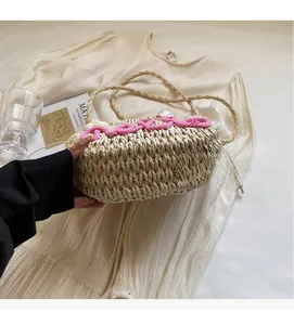 Detailed texture of straw beach bag with pink knit lettering and braided handles
