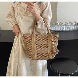 Close-up of hand-woven straw tote bag featuring intricate openwork patterns and wooden beads