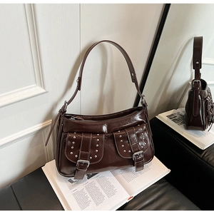 Detail of dark brown patent leather shoulder bag with silver rivet buckles and vintage pockets